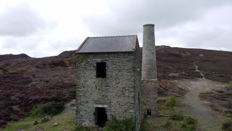 parys mountain abandoned brick chimney copper mining mill stone ruin aerial view low close right orbit to pull back