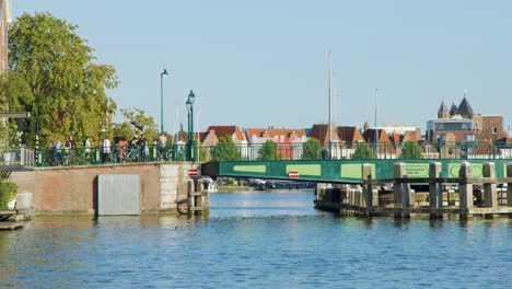 green drawbridge lifts for boats in haarlem, with people waiting and historic dutch buildings