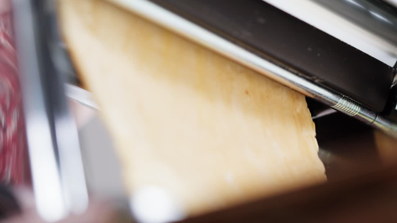 Close Up of Pasta Dough Being Rolled in a Pasta Machine