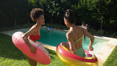 at pool party, diverse friends splashing water with inflatables, laughing and having fun