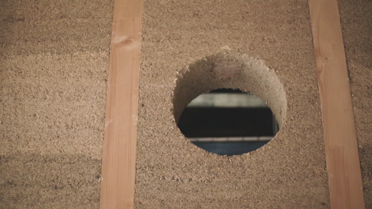 vista detallada de una pared de hormigón de cáñamo en marco de madera con una ventana de apertura redonda en construcción