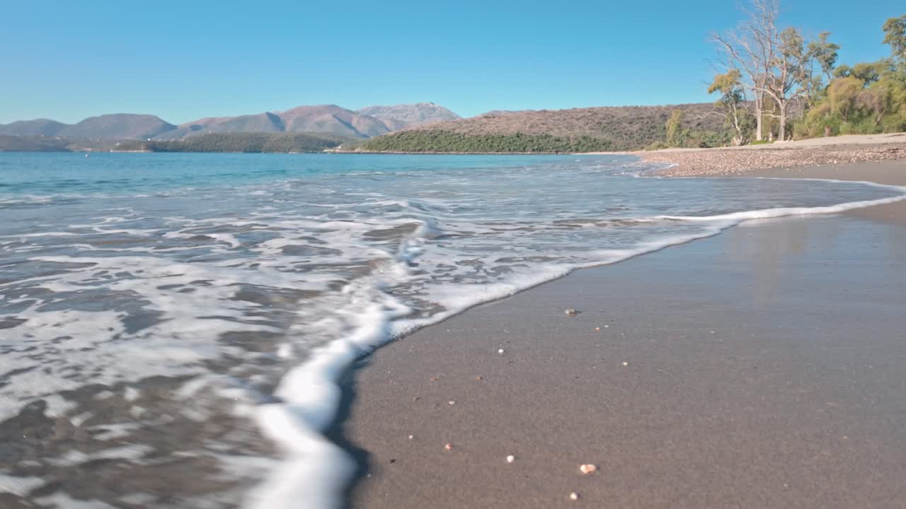 Waves run onto tropical deserted Mediterranean Greek beach low angle shot