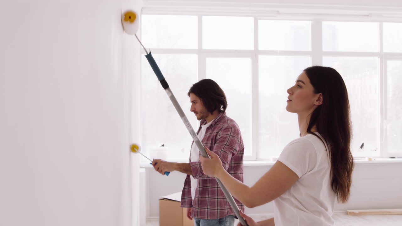 pareja pintando paredes en un nuevo hogar
