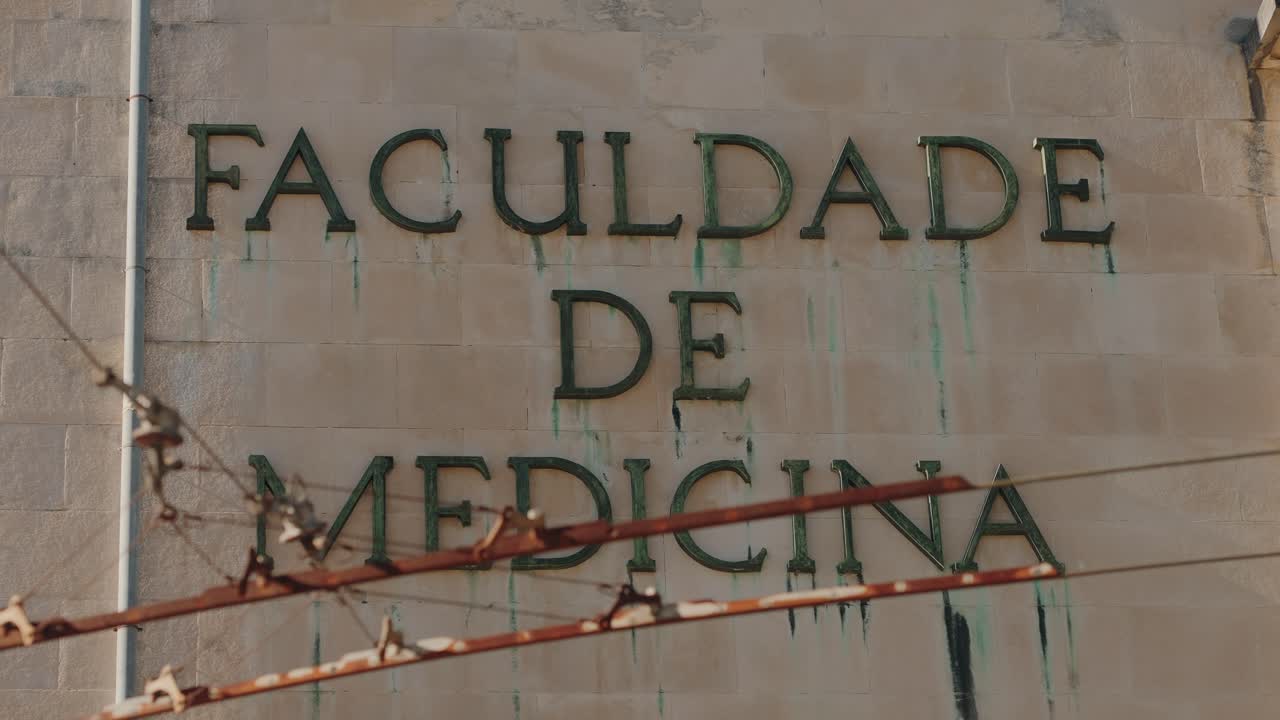 Exterior of Coimbra University’s Faculty of Medicine building with aged lettering