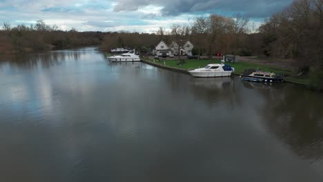 a serene riverside scene with boats moored along the bank under a cloudy sky