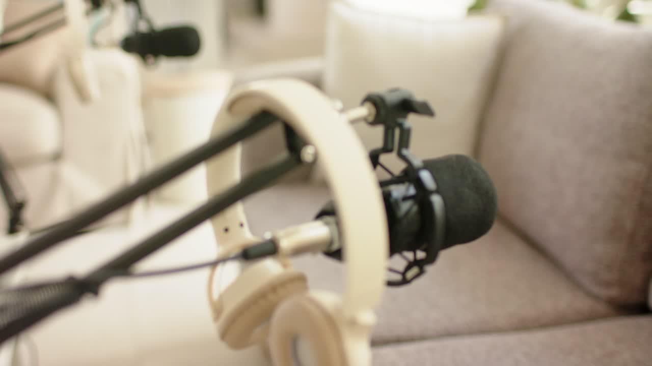 La telecamera sposta la messa a fuoco, mettendo in risalto microfono e cuffie per il podcasting casalingo.