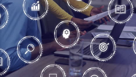 animación de iconos de negocios sobre diversos colegas que usan computadora portátil en la oficina