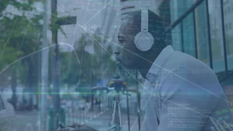 animation of financial data processing over african american man listening to music on the street