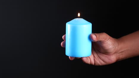 person holding a blue lit candle