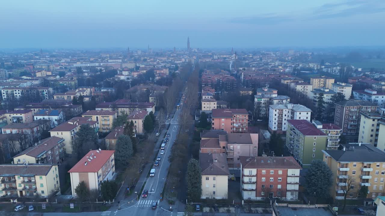 Paisagem aérea urbana de Cremona, no norte da Itália, com bairros de apartamentos, com a torre do sino de Torrazzo e silhuetas da catedral no plano de fundo, em uma manhã de inverno enevoada