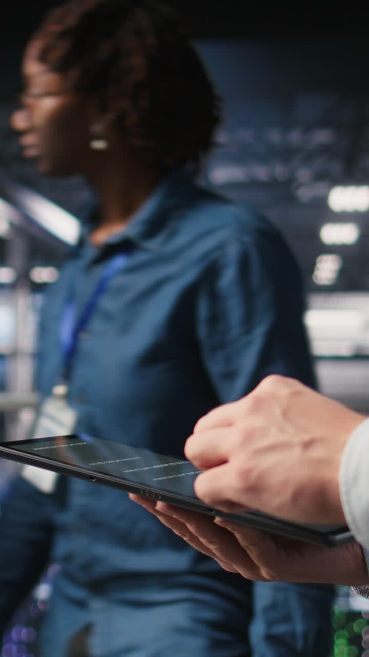 Vertical video Close up of data center software developer doing maintenance tasks on tablet