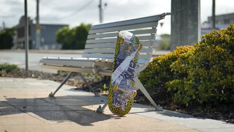 una patineta sentada en un banco del parque en una acera