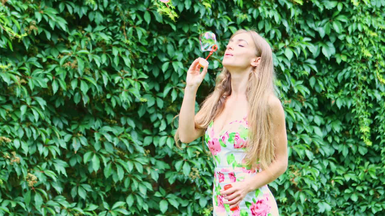 Una bella donna nel parco gioca soffiando bolle di sapone