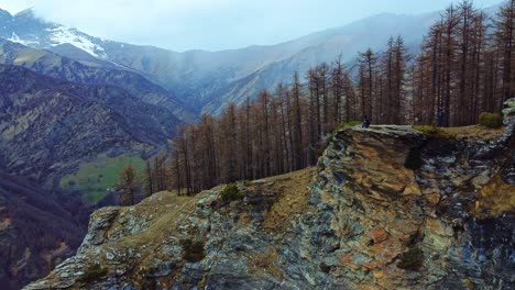 Panning-drone-shot-in-the-Italian-mountains-with-couple-standing-on-the-edge-of-a-cliff