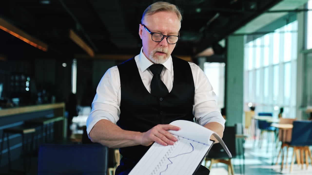 Businessman checking the documents in the office. Man in glasses demonstrates one of the charts.