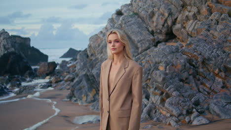 seashore model posing suit on rocky beach. closeup blonde model shooting shore