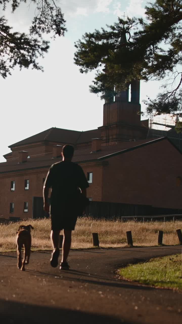 Man and Dog Walking Near Brick Building