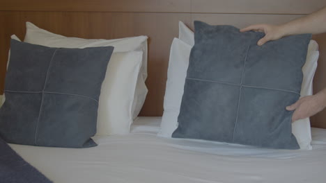 Decorative-pillow-being-placed-on-hotel-room-bed