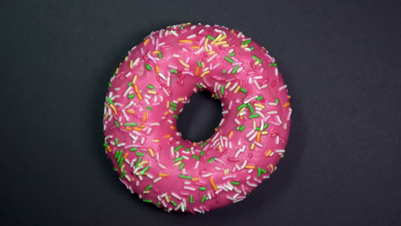 saboroso y fresco rosquilla rosquilla macro disparo de primer plano girando sobre un fondo negro.