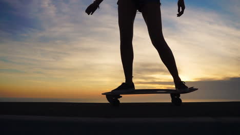 A-captivating-view-of-mountains-accompanies-the-slow-motion-depiction-of-a-beautiful-young-skateboarder-riding-her-board-in-shorts-along-a-mountain-road-at-sunset