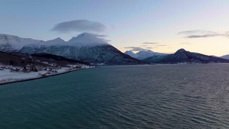 pintoresco paisaje de mar, montaña nevada y pueblo ártico en la noche polar en el norte de noruega