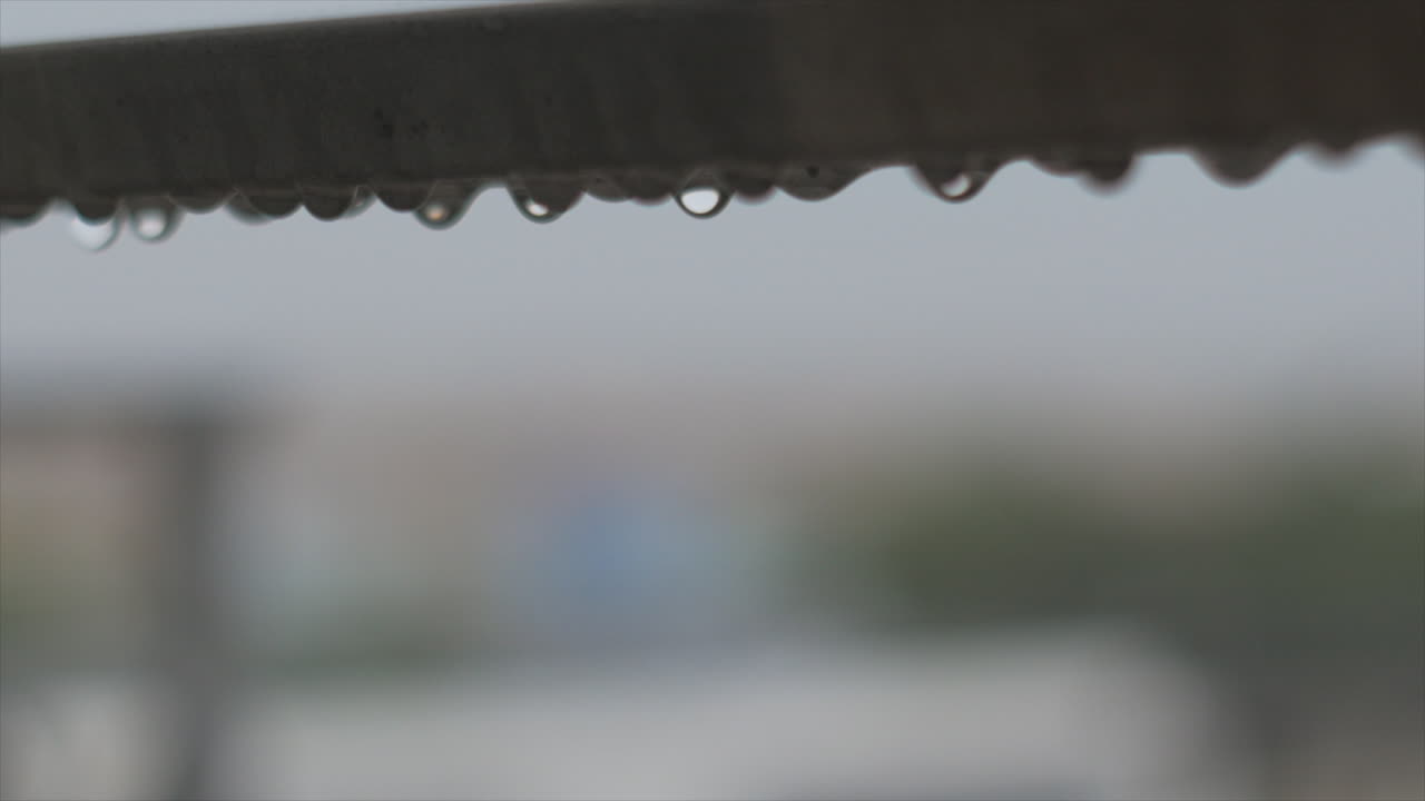 Rain droplets waving and falling on steel balcony guard, heavy rain