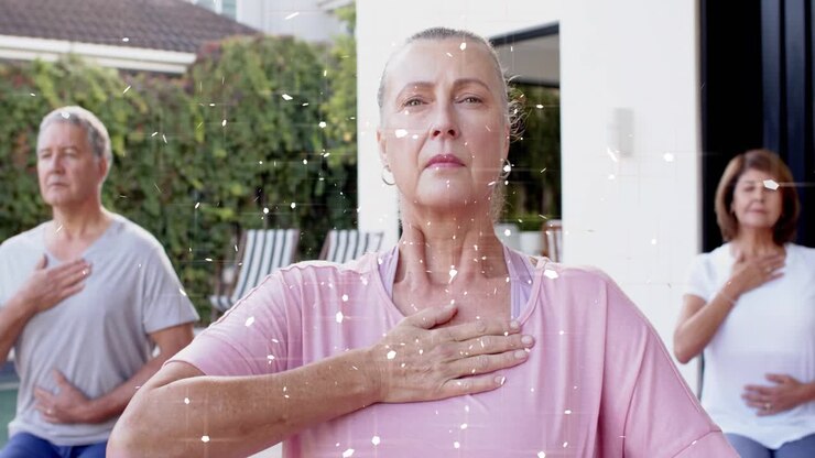 Moden kvinde knælende på måtte holder om bryst og mave, kameraet zoomer ind og viser funklende elementer over wellness