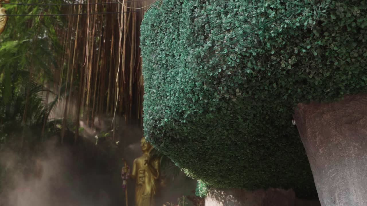 Mist Water Spraying Out of a Teal Colored Bush at the Buddhist Golden Mountain Temple in Thailand. Slow Motion.