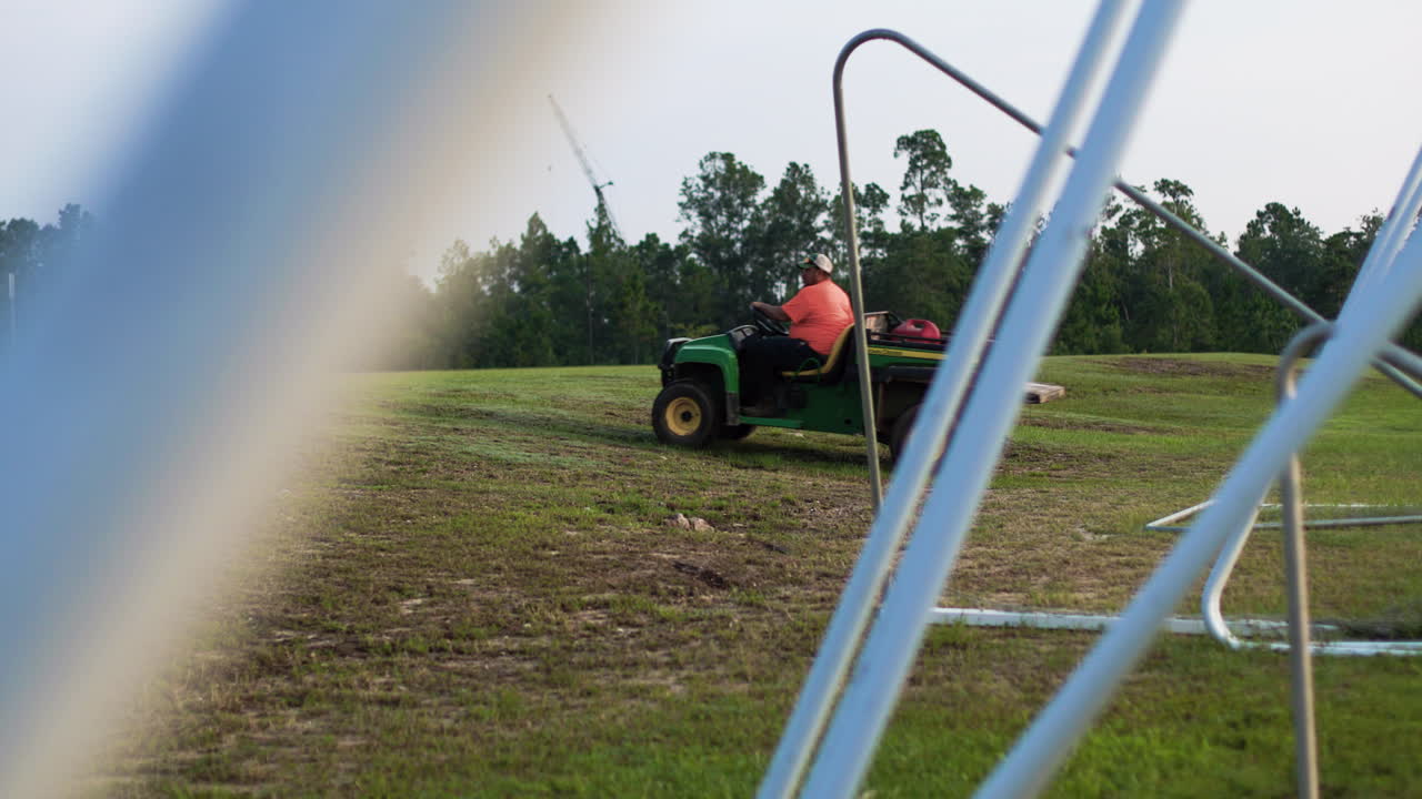 A field maintenance officer drives past soccer or futbol goal posts