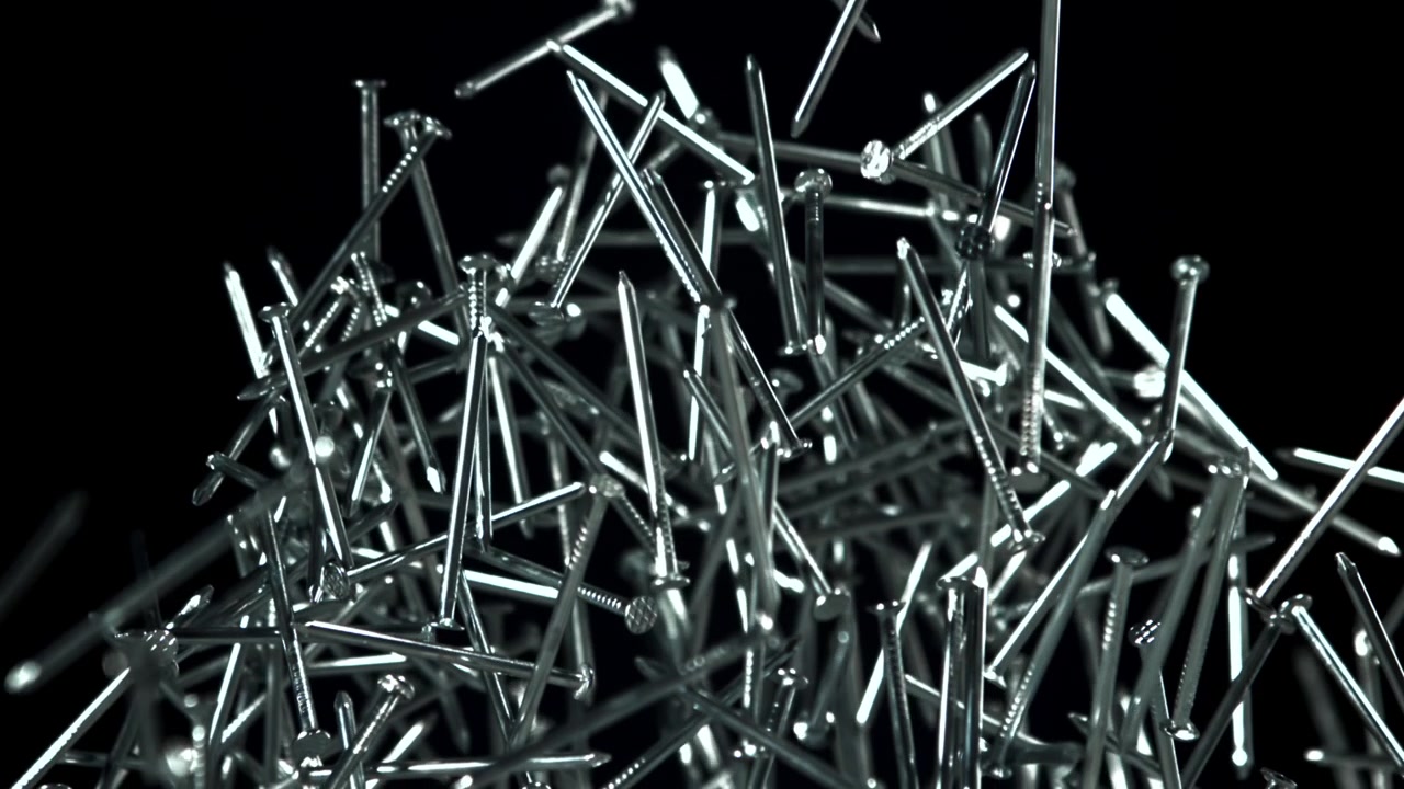 Magnetismin vetämät metallinaulat muodostavat abstraktin rykelmän mustalla taustalla