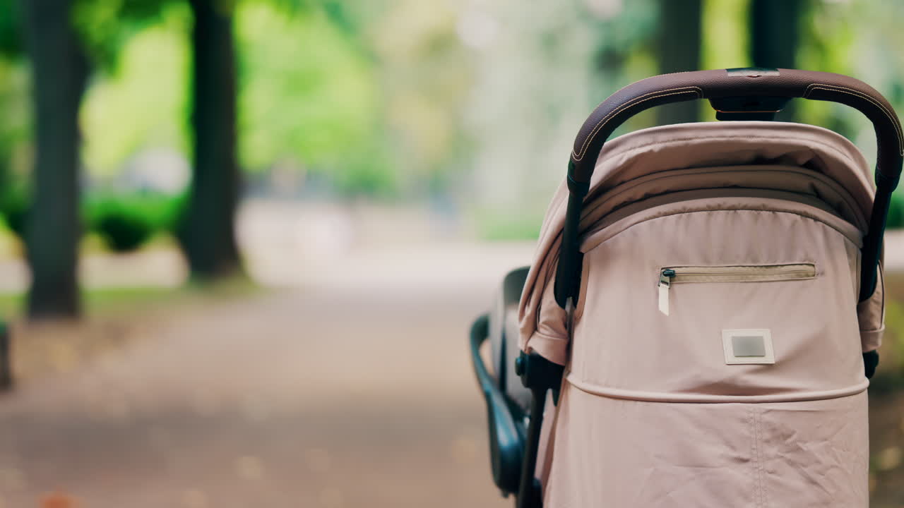 A beige baby stroller parked on a forest path in a park