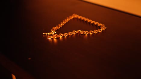 a gold semi-press chain laid out on elegant black wood