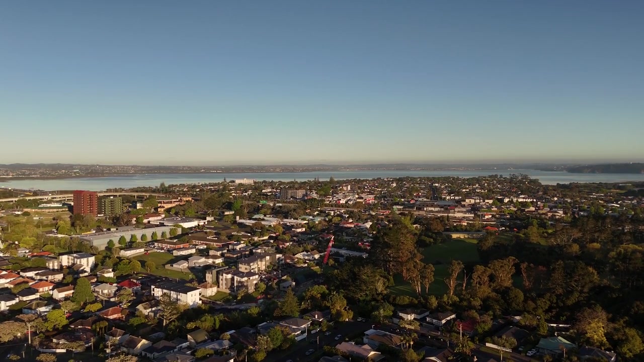 Wohnvororte und Waitematā Harbour bei Sonnenaufgang in Auckland, Neuseeland. Aufsteigende Luftaufnahme einer Drohne, mit Freiraum
