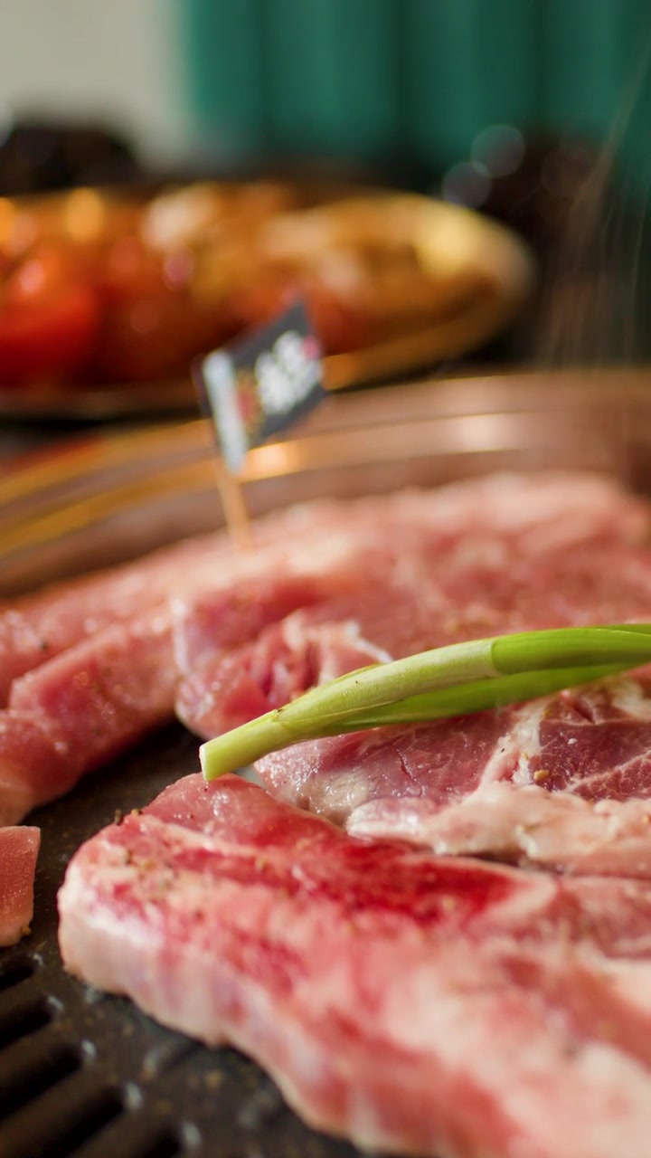 Daging sapi mentah dan daun bawang dipanggang, uap mengepul, kedalaman bidang dangkal, pencahayaan hangat