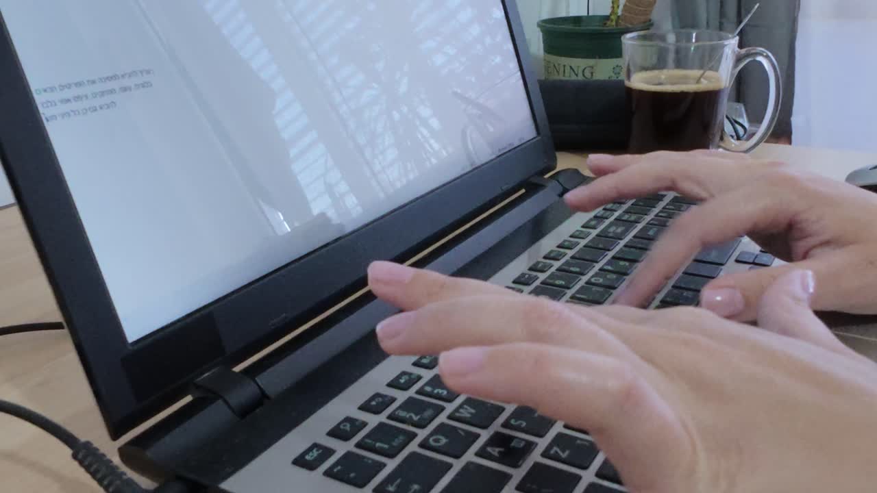 Close-up of wrist with smartwatch, hands actively typing on laptop