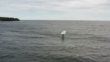 antena, persona activa surfeando en el lago superior en un día nublado sombrío