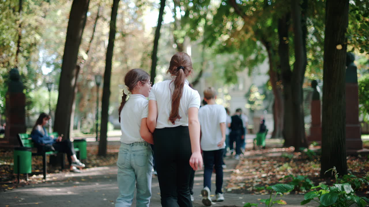 Chisinau, Moldova - September 25, 2025: Group of school children strolling under green trees in a sunny park