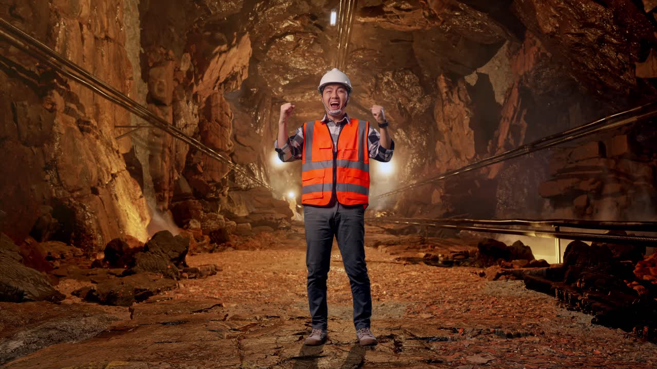 Full Body Of Asian Male Engineer With Safety Helmet Screaming Goal Celebrating Working In Underground Mine Tunnel