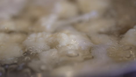 close up of cauliflower boiling in a pot on the stove - slow motion