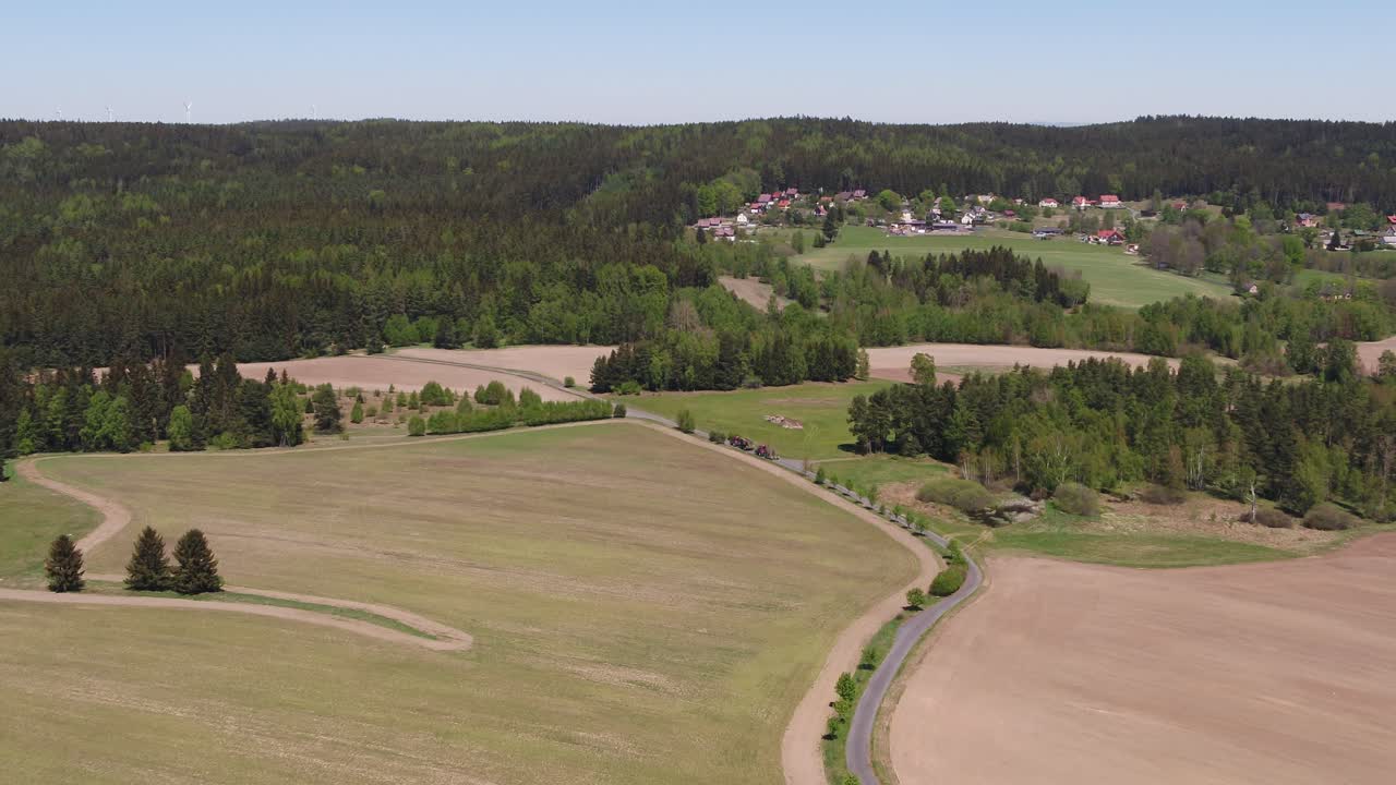 Drone zoom in over cultivated fields and rolling hills near Prague, Czech Republic, during clear sunny weather