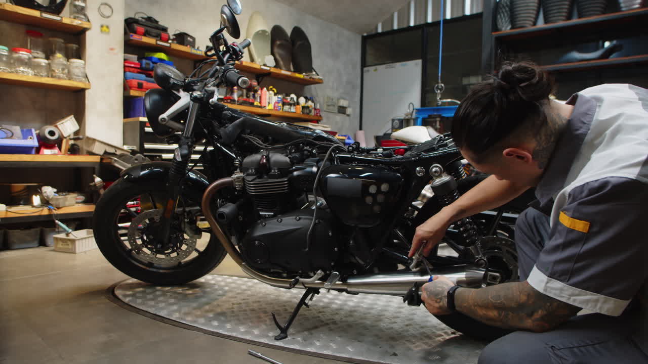 Tattooed Mechanic Checking Motorcycle Chain Tension