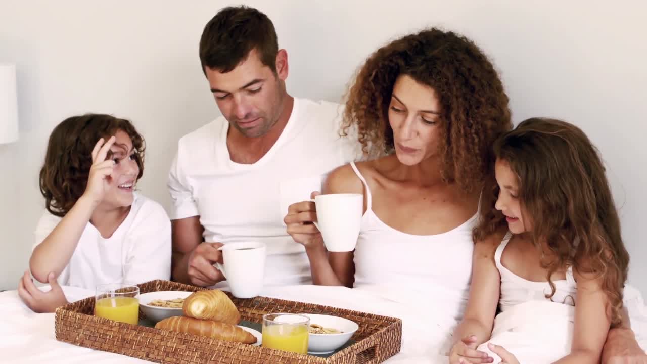 familia linda tomando el desayuno en la cama
