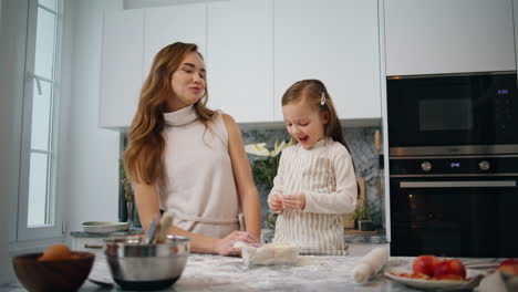 Cute-daughter-feeding-mother-with-apple-kitchen.-Positive-family-having-fun