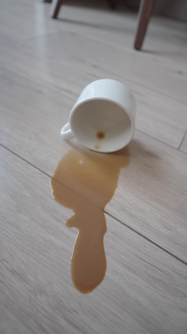 Hvit kopp og sølt kaffe på tregulv