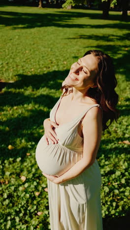 joyful pregnant woman embracing sunlight in a green park