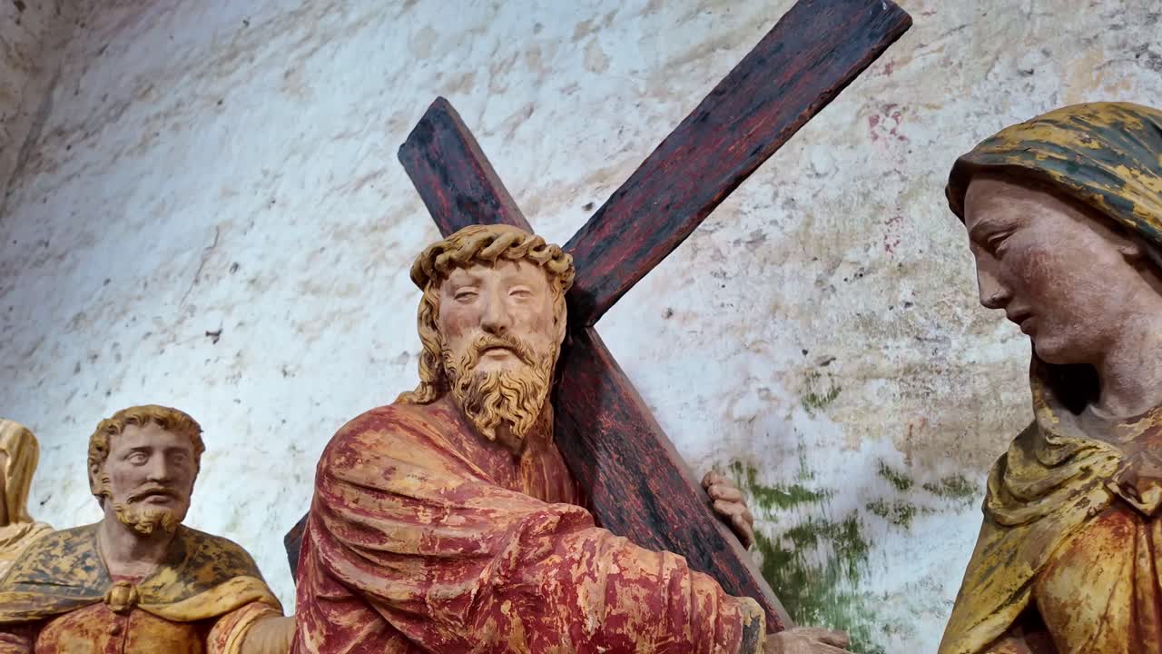Close-up of antique wooden statue of Jesus Christ carrying the cross, wearing crown of thorns