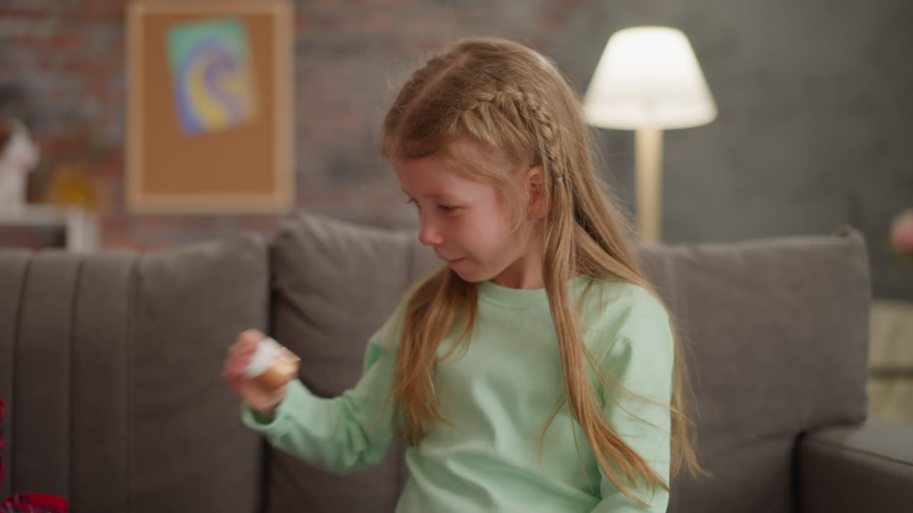 Pretty little girl with blonde hair shakes bottle with paint