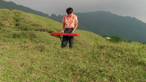 camera-slowly-reveals-Asian-man-playing-the-piano-on-a-mountaintop,-Lush-forest-mountains-in-the-background