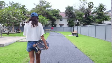 woman walking with skateboard in a park