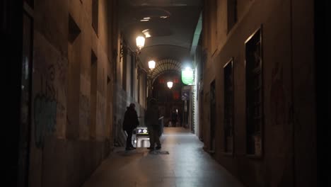 Alleyway-at-night-in-Madrid,-Spain,-with-people-standing-next-to-the-parking-lot-entrance